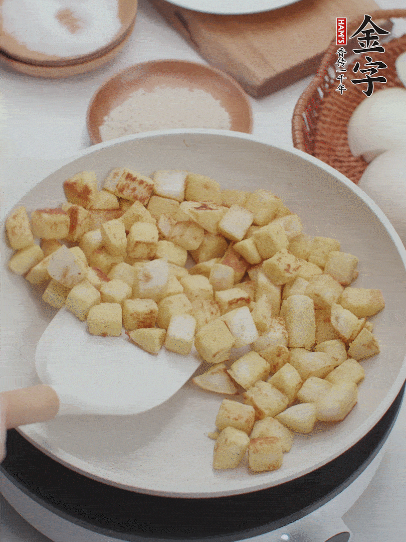 起鍋熱油，倒入饅頭丁，小火煎至蛋液凝固定型再翻面，饅頭丁部煎至金黃時(shí)盛起待用。
